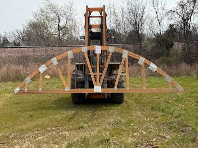 Large custom rounded wooden roof truss being transported by heavy equipment at Lakeside Truss Company in Crocker, Missouri. This image highlights our expert manufacturing process, strong engineering, and dependable delivery service that keeps local builders’ projects on schedule.